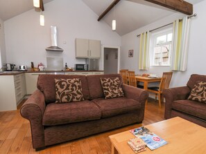 Uma sala de estar acolhedora com um sofá marrom, mesa de centro de madeira e um espaço de jantar com mesa e cadeiras de madeira.