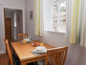 Uma sala de jantar com mesa de madeira, cadeiras e itens de café da manhã.