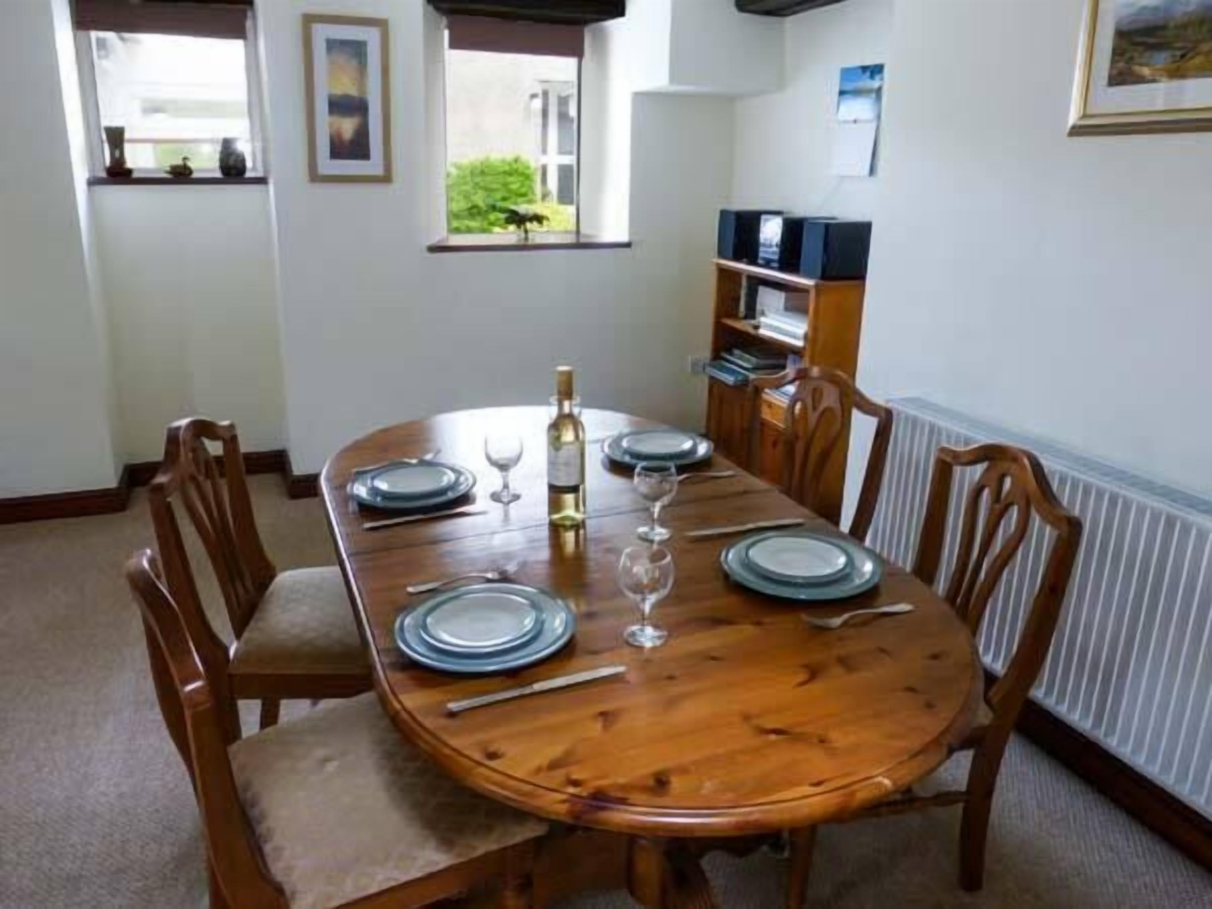 Comedor con una mesa de madera dispuesta para cuatro personas, rodeada de sillas de madera.
