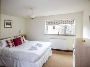 A hotel room with a bed, a radiator, a window with a view, and a bedside table.