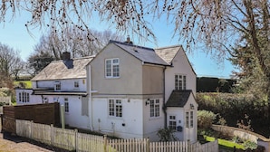 Ein zweistöckiges Haus mit weißer Fassade, einem Holzzaun und einem kleinen Garten.