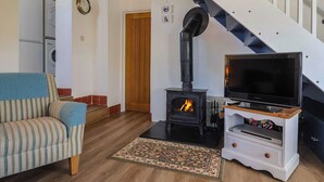 Ein Wohnzimmer mit einer Couch, einem Fernseher, einem Kamin und einer Treppe.