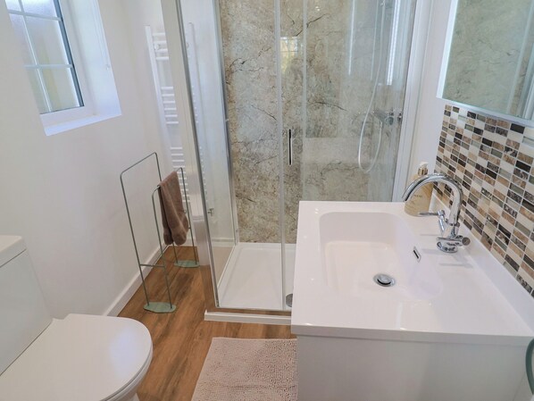 A bathroom with a shower, toilet, and sink. - The Old Smithy (Bridport)