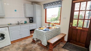 Cocina compacta con lavadora, un lavamanos y ventana con vistas a la vegetación.