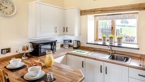 Una cocina moderna con armarios blancos, microondas negro, cafetera y una ventana con plantas.