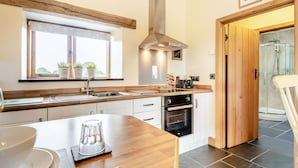 Una cocina moderna con encimera de madera, horno empotrado y una ventana con plantas.