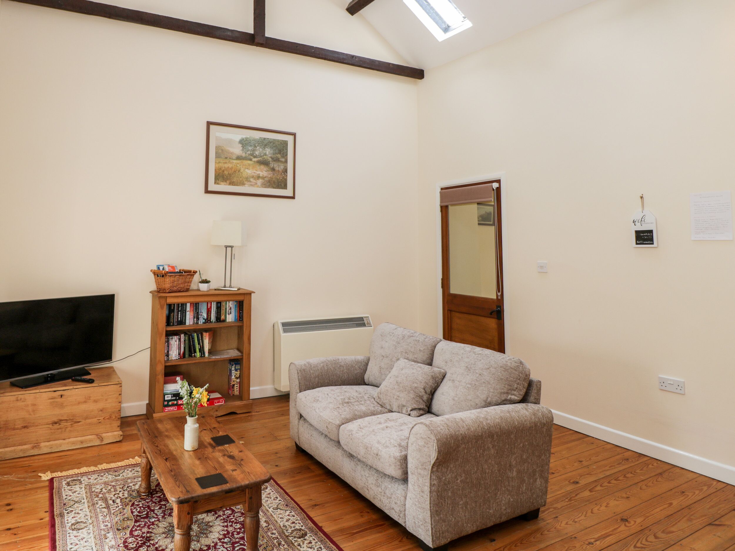 A living room with a sofa, a wooden table, a TV, a bookshelf, and a framed picture on the wall.