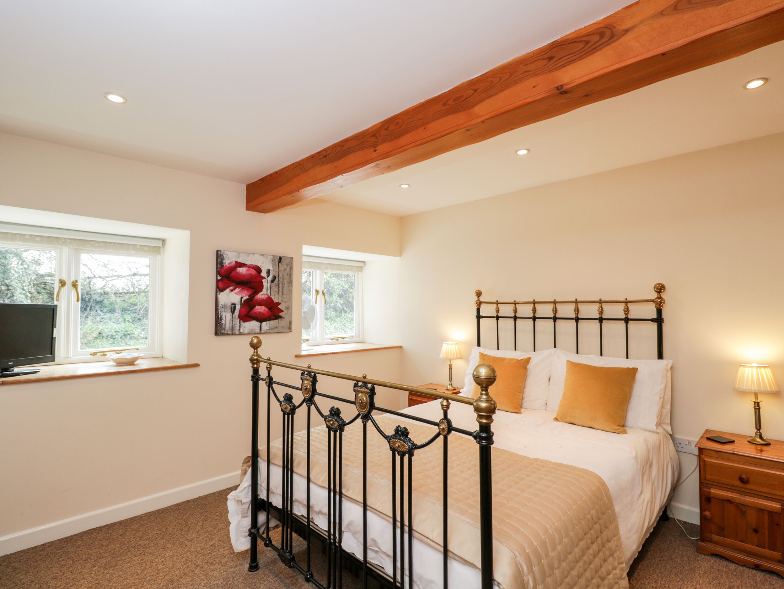 A bedroom with a bed, bedside tables, a window, and a painting on the wall.