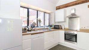 Una cocina moderna con armarios blancos, lavavajillas integrado, estufa y microondas.