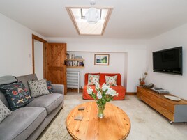 Una sala de estar con un sofá gris, un sofá rojo, una mesa de centro de madera, un televisor y una estantería.