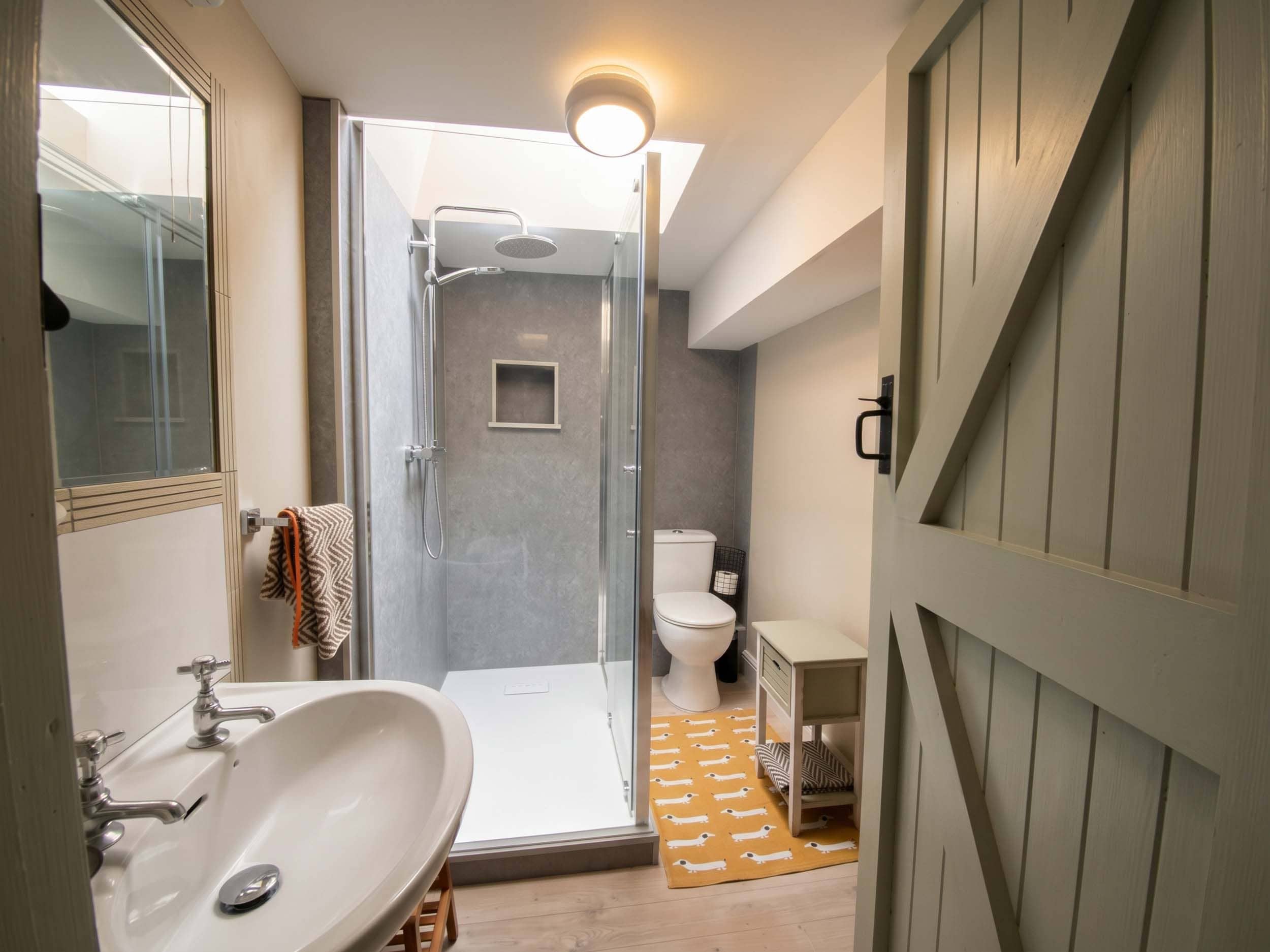 Un baño moderno con ducha de vidrio, un lavabo blanco y un inodoro.