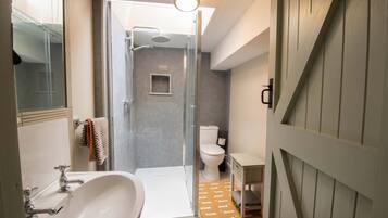 Un baño moderno con ducha de vidrio, un lavabo blanco y un inodoro.