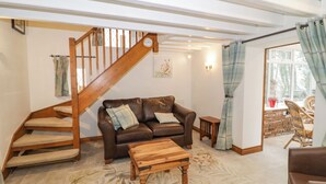 Un salón acogedor con un sofá de cuero marrón, una mesa de centro de madera y una escalera con barandillas de madera.