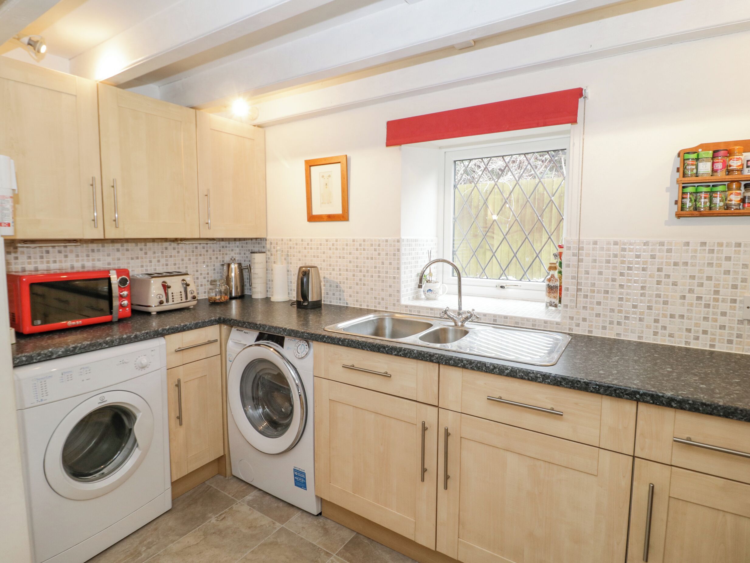 A compact kitchen with a washing machine, microwave, and toaster.
