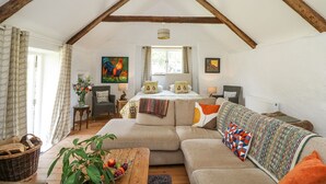 A cozy loft bedroom with exposed wooden beams, a large bed, and a view of the outdoors. - Hawthorn Cottage (Llandysul)