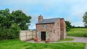 A stone house with a small porch and a gravel path leading to the entrance. - Rose Cottage (Monmouth)