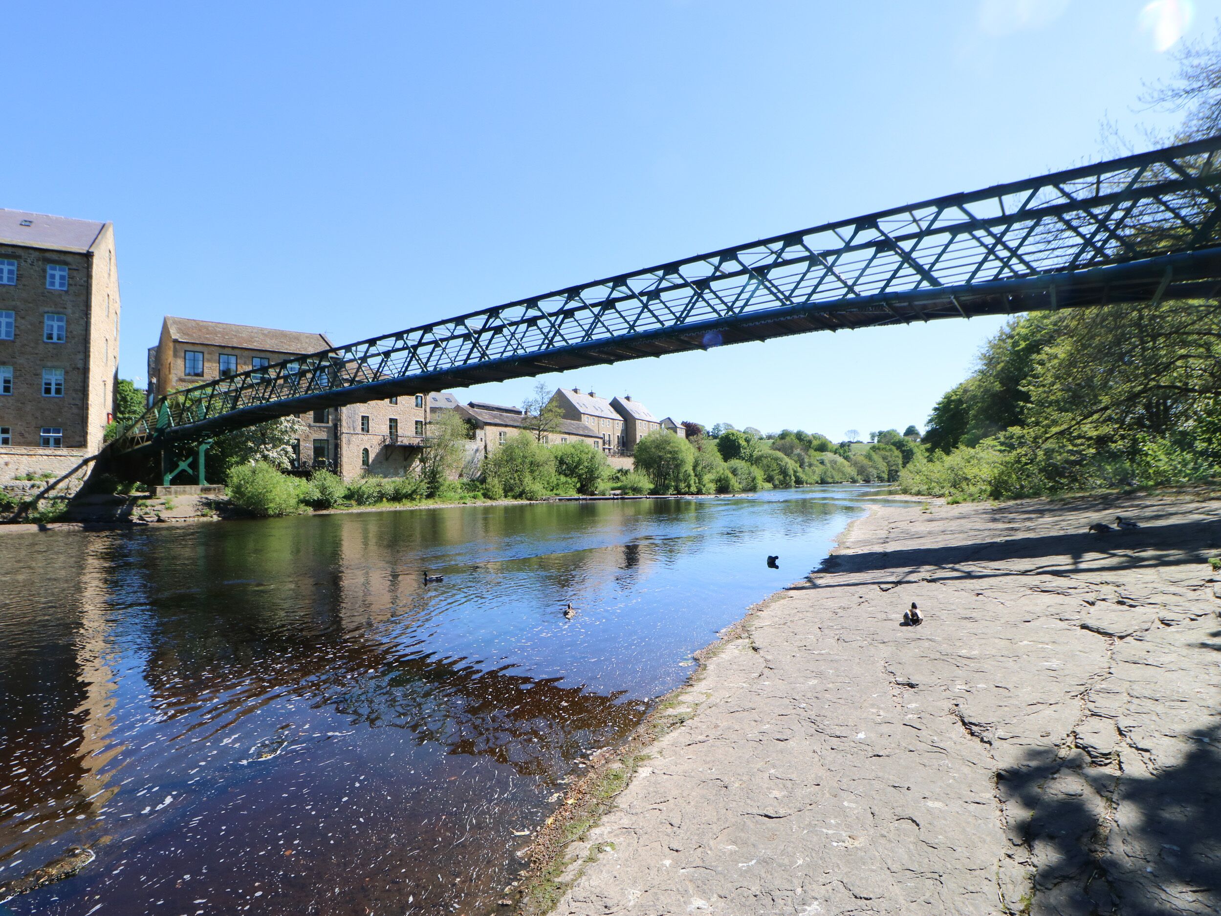A river under a bridge with buildings on the opposite bank.