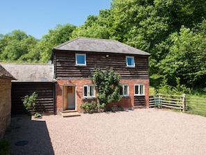 A two-story wooden house with a gravel driveway and a wooden fence. - Stable Cottage (Tenbury Wells)