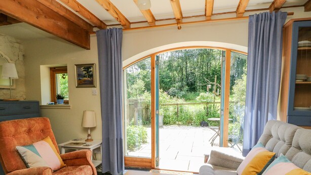 A cozy living room with a fireplace, a sofa, a chair, and a table. - The Garden Flat (Fort William)