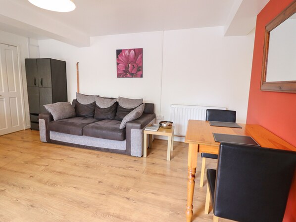 Una sala de estar con sofá, mesa de comedor y una computadora portátil.