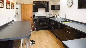Una cocina compacta con armarios oscuros, una encimera negra y un tragaluz sobre el fregadero.