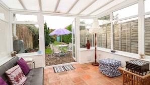 A conservatory with a patio area featuring a table, chairs, and a lamp. - Duck Cottage (King's Lynn)