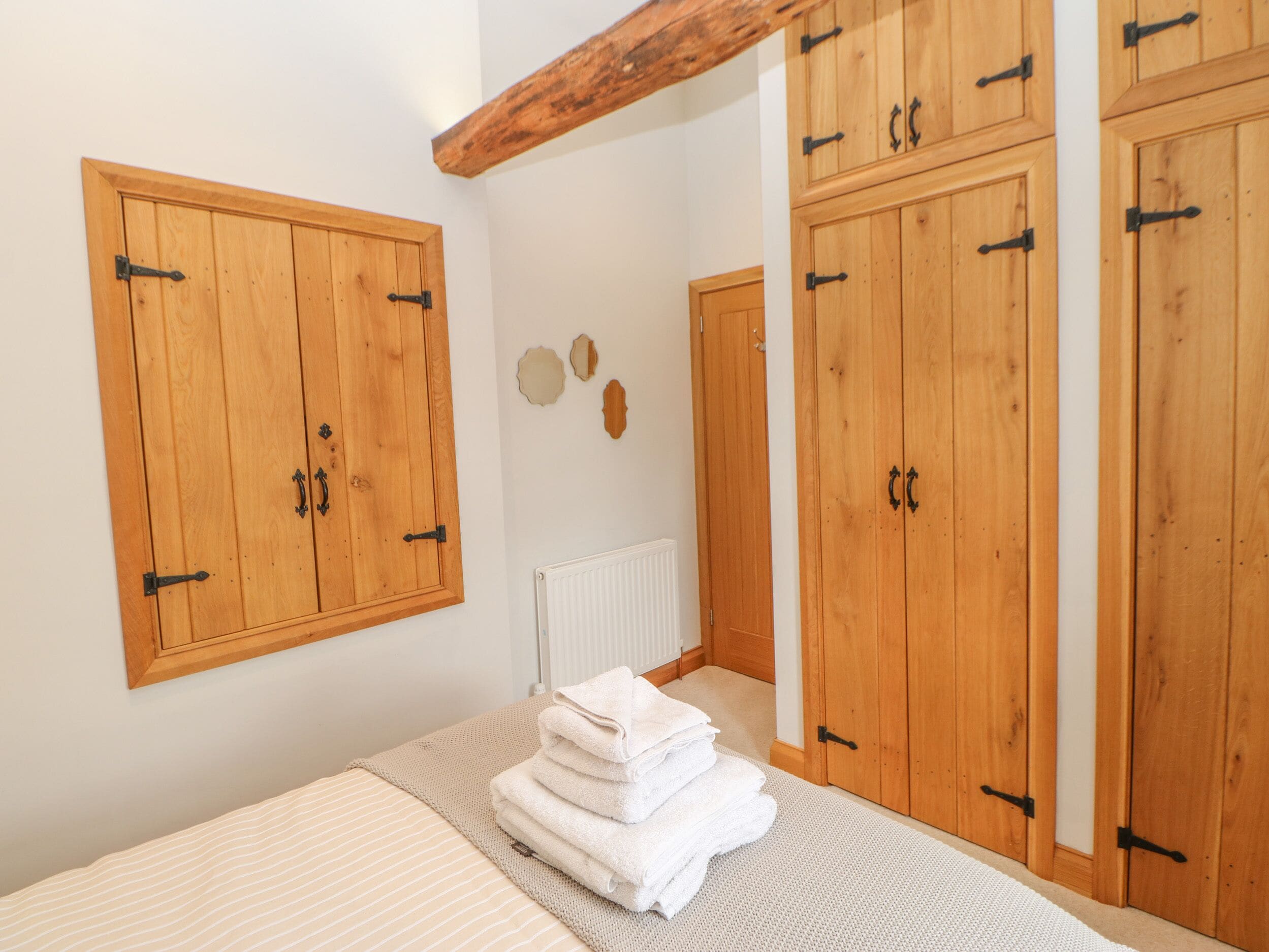 Un dormitorio con armarios de madera, una cama con manta a rayas y un radiador.