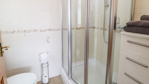 A modern bathroom with a glass-enclosed shower, a toilet, and a vanity with drawers. - Smithy Cottage (Cemaes Bay)