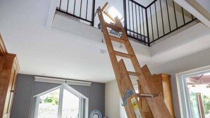Een keuken met houten kasten, een raam en een houten ladder die tegen de muur staat.