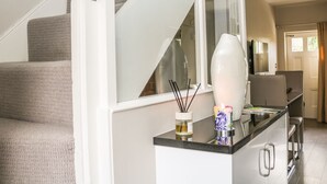 A modern kitchen with a black countertop, stainless steel appliances, and a white vase with a candle. - Ash Cottage (Bakewell)