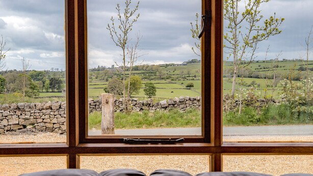 A view through a window with a stone wall and trees, a stone wall, and a stone wall. - Robin Cottage (Leek)