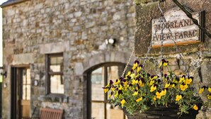 A stone building with a hanging flower basket and a sign that reads "MORLAND VIEW FARM". - Robin Cottage (Leek)