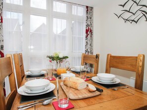 A dining table set with plates, glasses, a pitcher of orange juice, a loaf of bread, and a vase with flowers. - Swallows Cottage (Shrewsbury)