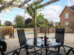 An outdoor seating area with a round table, chairs, and a bottle of wine. - Swallows Cottage (Shrewsbury)