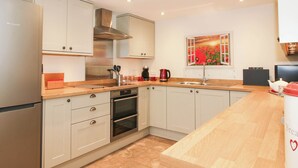 Una cocina moderna con armarios blancos, electrodomésticos de acero inoxidable y encimera de madera.