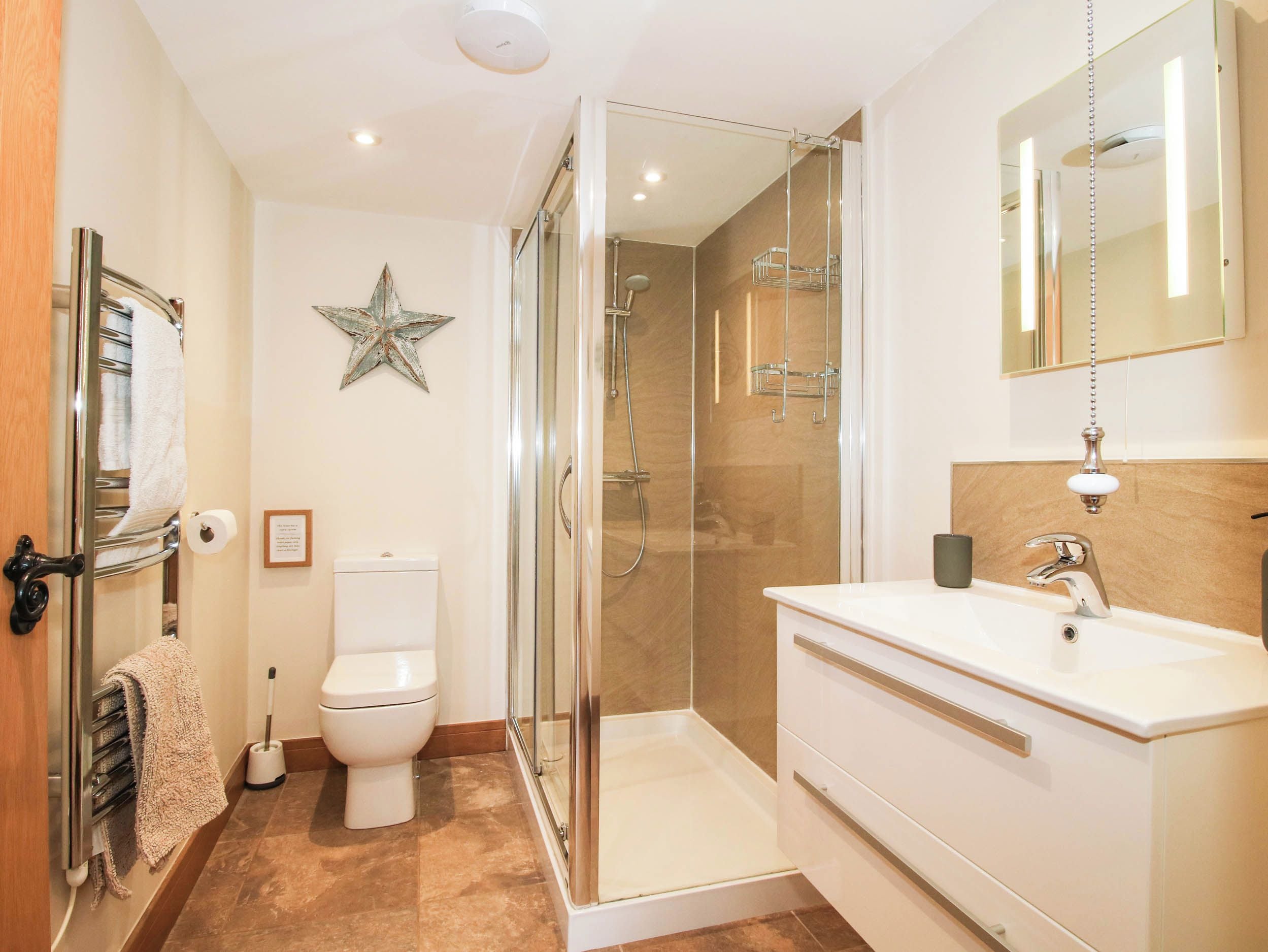 A modern bathroom with a glass-enclosed shower, a white toilet, and a vanity with a mirror.