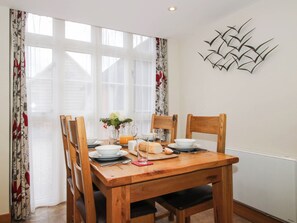 A dining area with a wooden table, chairs, and a decorative wall piece. - Swallows Cottage (Shrewsbury)