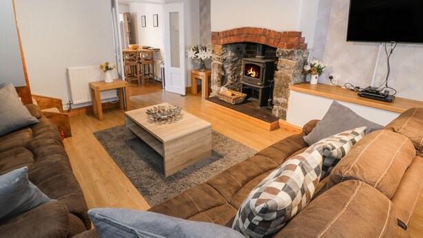 A cozy living room with a fireplace, wooden furniture, and a flat-screen TV. - Tryfan (Caernarfon)