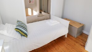 A bedroom with a bed, a bedside table, a wooden bench, a radiator, and a mirror. - Tryfan (Caernarfon)