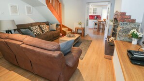 A spacious living area with a brown leather sofa, a wooden coffee table, and a staircase leading to an upper level. - Tryfan (Caernarfon)