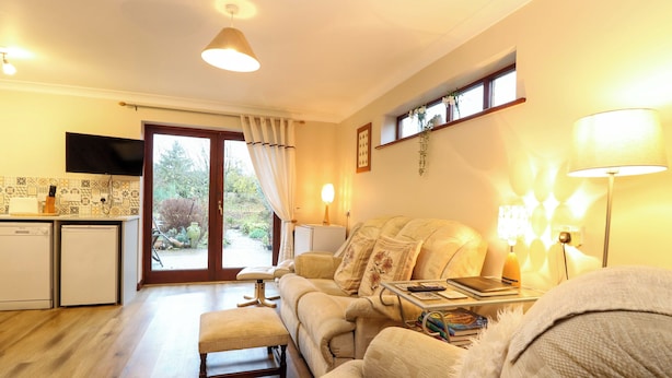 A cozy living room with a sofa, ottoman, and a dining area with a small kitchen. - Kingfisher (Diss)