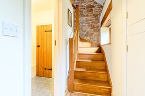 A wooden staircase with a stone wall, leading to a door with a black handle. - The Bothy (Ross-on-Wye)