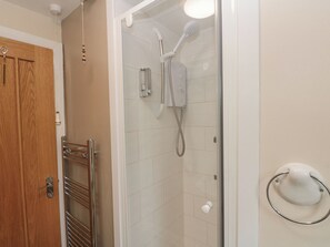 Bathroom features a glass-enclosed shower with handheld showerhead and wall-mounted faucet.