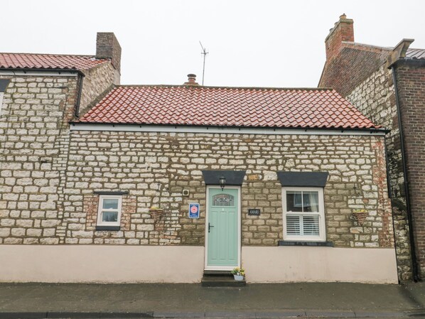 Traditional stone building with a classic architectural style, featuring a green door and a sign reading 'AMARI'.