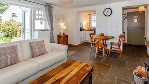 Una sala de estar acogedora con un sofá, una mesa de centro de madera y un comedor con mesa y sillas.