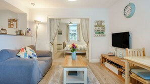 Una sala de estar moderna con un sofá, una mesa de centro, un televisor y una estantería.