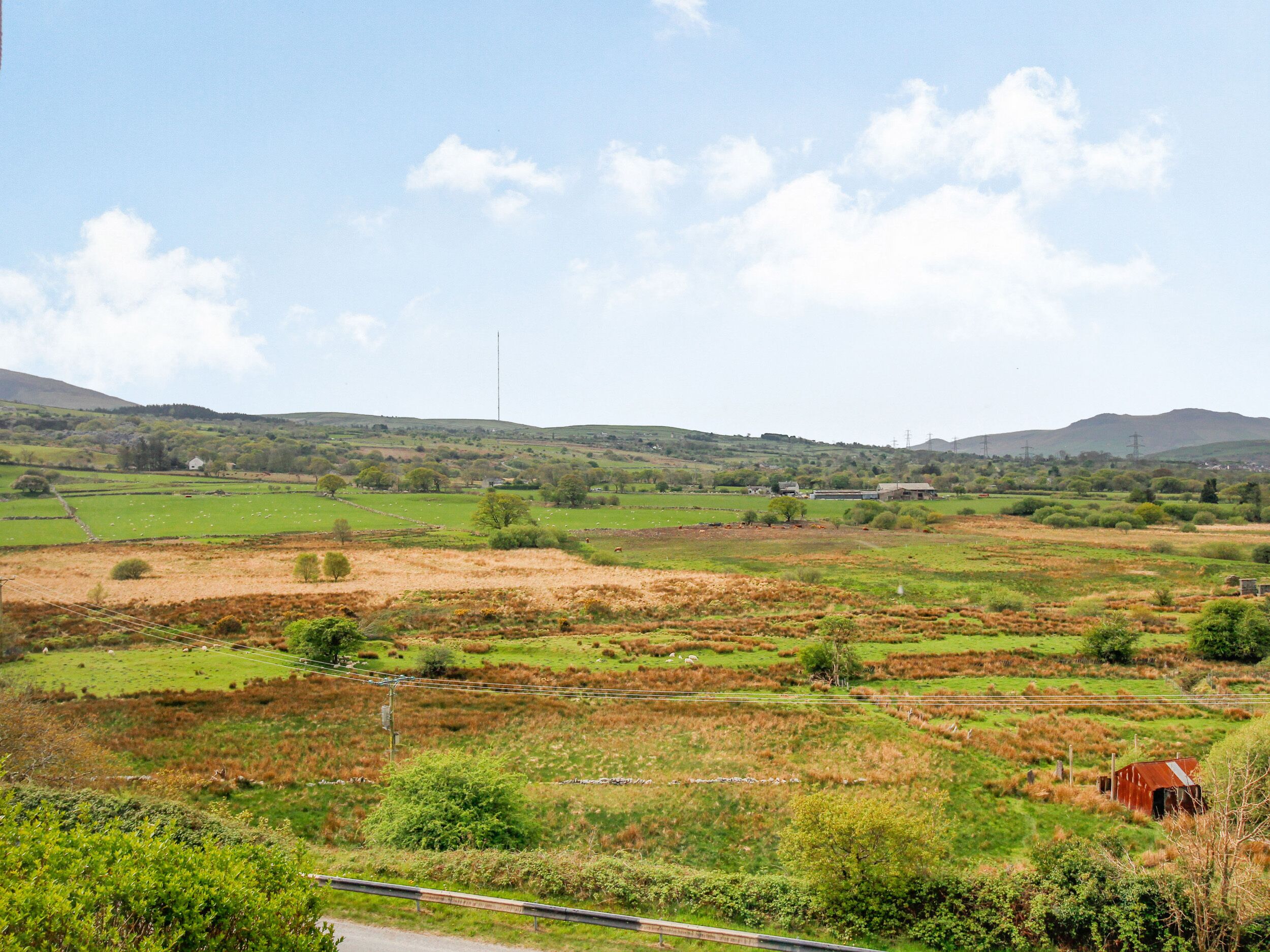 A rural landscape with fields, a few scattered buildings, and a distant hill.