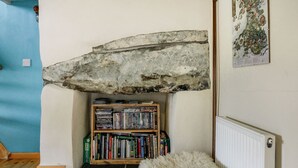 Un rincón acogedor para leer con una estantería, un manto mullido blanco y una viga de piedra rústica en el techo.