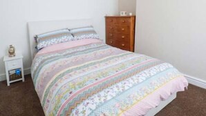 A bedroom with a bed, a dresser, and a nightstand. - Flat 1 (Bridlington)