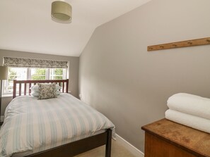 Un dormitorio con cama, ventana con vistas, mesita de noche y lámpara.
